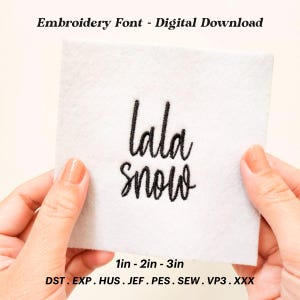 Pode incluir: Um quadrado de tecido branco com bordado preto que diz "lala snow". O tecido é segurado por duas mãos. O texto abaixo do bordado diz "1in - 2in - 3in" e "DST. EXP. HUS. JEF.PES.SEW.VP3.XXX".