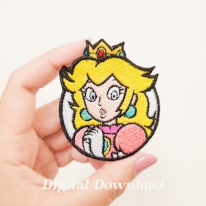 Puede incluir: Parche bordado con la Princesa Peach de Super Mario. El parche la muestra con una corona amarilla, pelo rubio y un vestido rosa. El parche redondo tiene un borde blanco.
