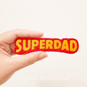 May include: Red and yellow embroidered patch with the word "SUPERDAD" in yellow letters.