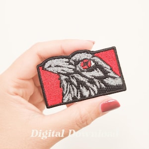 Könnte beinhalten: Gestickter Aufnäher mit einem stilisierten Rabenkopf mit rotem Auge, vor einem roten rechteckigen Hintergrund. Der Rabe ist in Grau- und Schwarztönen dargestellt, mit aufwendigen Stickdetails. Der Aufnäher wird in einer Hand gehalten.
