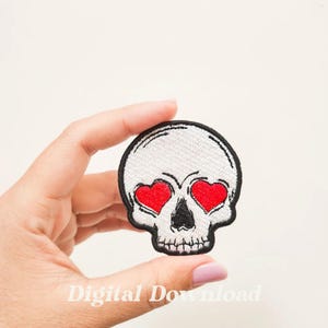 Könnte beinhalten: Weißer gestickter Totenkopf-Patch mit roten Herzaugen.