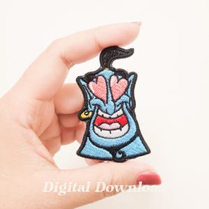 May include: A blue embroidered patch of the Genie from Aladdin with hearts for eyes. The Genie is smiling with his mouth open and has a gold earring in his left ear.