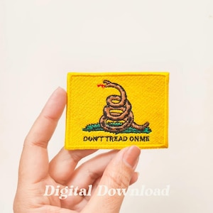Può includere: Una toppa ricamata gialla con un serpente avvolto e il testo "Don't Tread On Me".