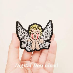 May include: An embroidered iron-on patch featuring a white angel with black outlines and red teardrop-shaped eyes. The angel is depicted with its head resting on its hands, looking down.