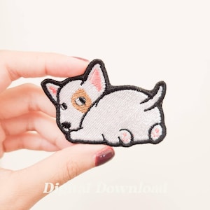 May include: White embroidered patch of a cartoon bull terrier dog with black outlines and pink ears. The dog is lying down with its head turned to the side.