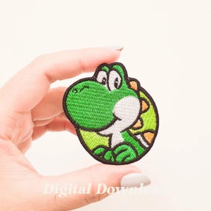 Puede incluir: Parche verde bordado para planchar de Yoshi, un personaje de la serie de videojuegos Super Mario. Yoshi es una criatura parecida a un dinosaurio con una gran sonrisa y un cuerpo verde.