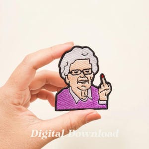 Puede incluir: Parche bordado para planchar con un dibujo animado de una mujer mayor con el pelo gris, gafas y un jersey morado, haciendo el dedo corazón.