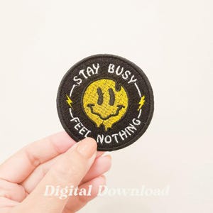 Könnte beinhalten: Schwarzer und gelber gestickter Aufnäher mit einem Smiley und dem Text "Stay Busy Feel Nothing".