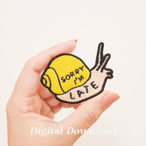 May include: A yellow embroidered iron-on patch of a snail with the text "Sorry I'm Late" on the shell.