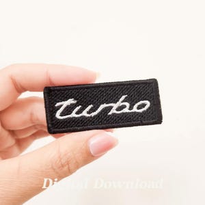 Puede incluir: Parche bordado negro con letras blancas que dicen "Turbo".