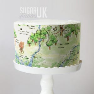 a cake decorated with a Winnie the Pooh-themed map, including illustrations of various landmarks and locations from the classic story.