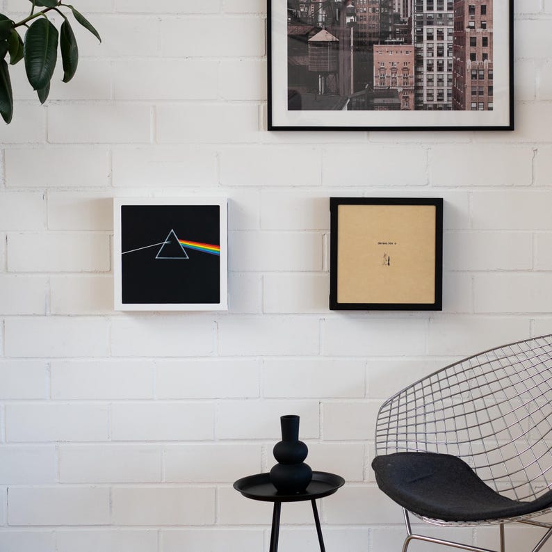 Pode incluir: Uma exposi&ccedil;&atilde;o de parede com arte e decora&ccedil;&atilde;o emolduradas. A obra de arte inclui uma impress&atilde;o de paisagem urbana em preto e branco, uma impress&atilde;o emoldurada em preto com texto e uma impress&atilde;o emoldurada com um fundo preto e um design de prisma de arco-&iacute;ris.
