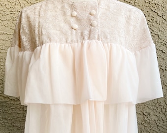 May include: A delicate, pale pink, lace-trimmed nightgown with a ruffled skirt and button closures at the neckline.