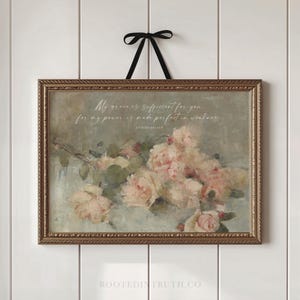 May include: A rectangular wall art piece in a textured gold frame with a black ribbon hanger. The print features a soft, painterly arrangement of pale pink roses and green leaves against a muted grey background, with the text My grace is sufficient for you, for my power is made perfect in weakness. 2 Corinthians 12:9.