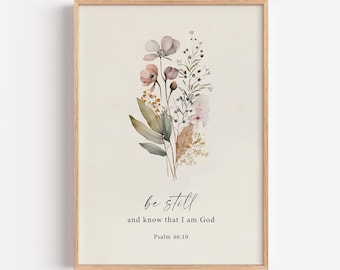 May include: A framed wall art print featuring a watercolor illustration of a wildflower bouquet in muted pink, green, and brown tones. Below the flowers, the text reads: "be still and know that I am God" followed by "Psalm 46:10" in black font.