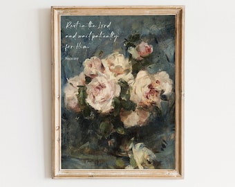 May include: A framed wall art print featuring an oil painting of pale pink and white roses in a dark blue and grey setting. The text reads: Rest in the Lord and wait patiently for Him. Psalm 37:7. The frame is a light wood with a textured finish.