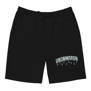 Puede incluir: Pantalones cortos deportivos negros con cintura con cordón y bolsillos. Los pantalones cortos tienen el texto "UNCOMMON DIFFERENT" en una fuente azul claro en la pierna inferior derecha. Hecho de material suave.