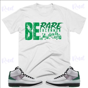May include: White t-shirt with green text that reads "BE RARE UNCOMMON DIFFERENT".  A pair of white and green sneakers with black accents.