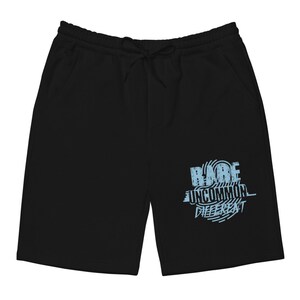 Puede incluir: Pantalones de ch&aacute;ndal negros con un estampado gr&aacute;fico azul que dice "RARE UNCOMMON DIFFERENT".