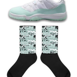 Puede incluir: Una zapatilla deportiva blanca y verde menta con suela blanca se muestra sobre dos calcetines negros. Los calcetines tienen un patrón verde menta y negro con la palabra "UNCOMMON" repetida.