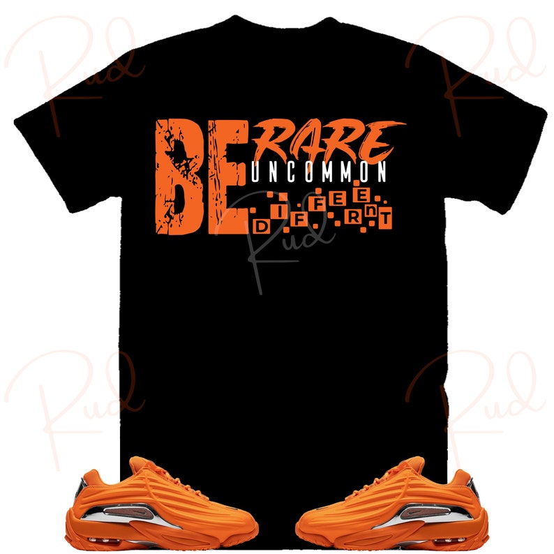 Puede incluir: Una camiseta negra con el texto "BE RARE UNCOMMON" en naranja. El texto est&aacute; en una fuente en negrita y de bloques. La camiseta se combina con un par de zapatillas naranjas con suela blanca.