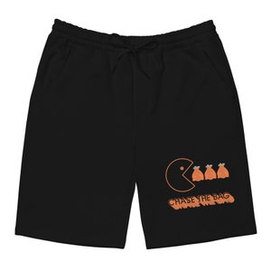 Pode incluir: Cal&ccedil;as de moletom pretas com um gr&aacute;fico de Pac-Man laranja e o texto "CHASE THE BAG" impresso na perna direita.