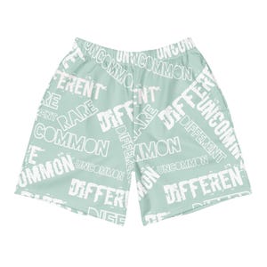 Puede incluir: Pantalones cortos deportivos verde claro con un patrón de texto blanco repetido. Las palabras "UNCOMMON", "DIFFERENT", "RARE" y "COMMON" son visibles en una fuente distorsionada. Los pantalones cortos están hechos de un material ligero.
