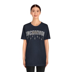 May include: A dark blue t-shirt with the text "UNCOMMON RARE DIFFERENT" printed on the front. The text is in a white font with a gray outline.