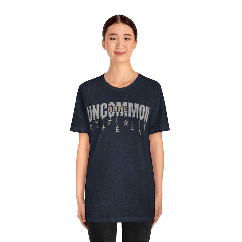 May include: A dark blue t-shirt with the text "UNCOMMON RARE DIFFERENT" printed on the front. The text is in a white font with a gray outline.