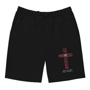 Może przedstawiać: Czarne szorty z talią ze sznurkiem i kieszeniami. Czerwony krzyż z napisem "Blessed" i "God" znajduje się na prawej nogawce. Inicjały "R.U.D." znajdują się poniżej.