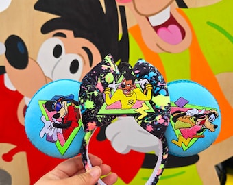 Può includere: Un paio di orecchie da topo fantasiose con un motivo a spruzzi nero e neon. Le orecchie presentano personaggi dei cartoni animati in stile retrò anni '90. La fascia è bianca con un motivo in bianco e nero.