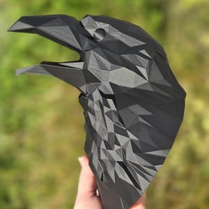 May include: A black, 3D printed raven head sculpture with a geometric design. The sculpture is made of many small triangles that create a textured surface.