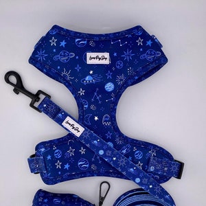 May include: A blue dog harness, leash, and poop bag holder with a space-themed print featuring stars, planets, and a UFO. The text "Love My Dog Shop" is printed on the harness and poop bag holder.