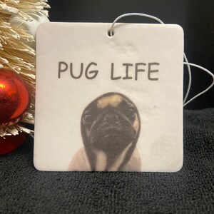 Pu&ograve; includere: Profumatore per auto bianco con l'immagine di un carlino nero e marrone e la scritta "PUG LIFE" stampata su di esso.