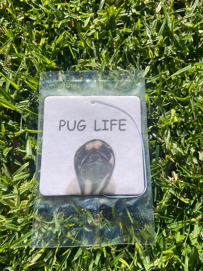 Pu&ograve; includere: Un profumatore per auto bianco con un'immagine di un carlino in bianco e nero e la scritta "PUG LIFE" stampata su di esso.