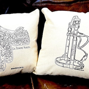 Pode incluir: Duas capas de almofada brancas com desenhos de linha preta de equipamentos equestres. A almofada da esquerda apresenta uma sela com o texto "La Femme Nakita" e um endereço de site. A almofada da direita apresenta um arreio de cavalo com o texto "Peter  Dood" e um endereço de site.