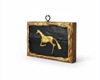 Può includere: Opera d'arte da parete rettangolare con un cavallo dorato in movimento su sfondo nero. Il cavallo è incorniciato da un bordo dorato strutturato. Un piccolo anello di metallo nero è attaccato in alto per appenderlo.