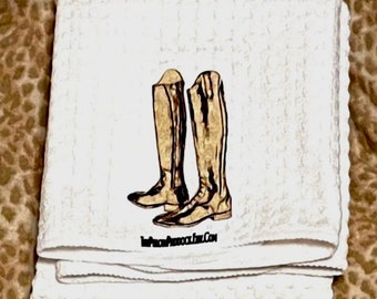 Può includere: Un asciugamano da cucina bianco con un'illustrazione marrone di due stivali alti da equitazione. Il testo "ThePeacockRoom.Com" è stampato sotto gli stivali.