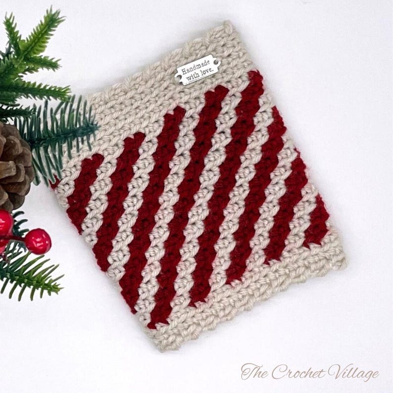 May include: A crocheted cup cozy with red and white stripes. The cozy has a tag that says "Handmade with love."