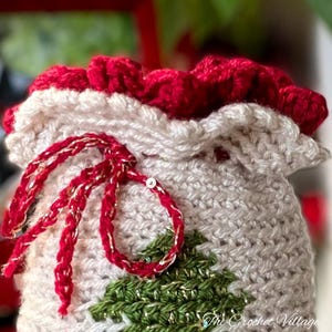 May include: A crocheted Christmas stocking with a red and white ruffle top, a green and gold tree design, and a red and gold ribbon.