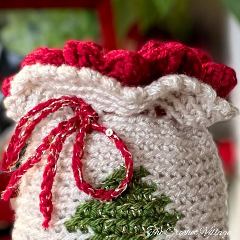 May include: A crocheted Christmas stocking with a red and white ruffle top, a green and gold tree design, and a red and gold ribbon.