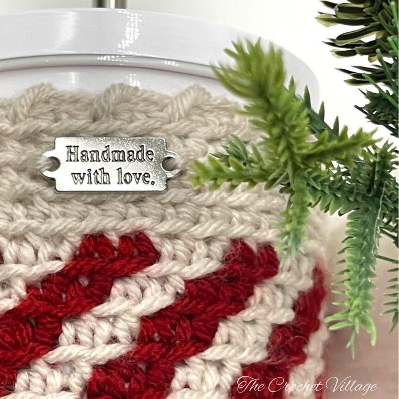 May include: A crocheted cup cozy in red and white stripes with a silver tag that reads "Handmade with love."
