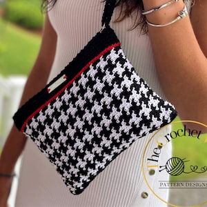 May include: A black and white crocheted handbag with a red stripe and a white label that says "The Crochet Village Pattern Designs".