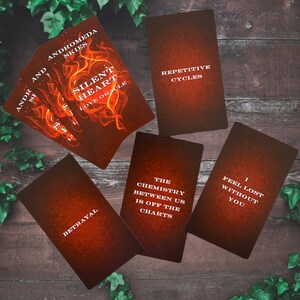 Puede incluir: Cinco cartas de tarot con un fondo naranja fuego y texto blanco. Las cartas se titulan "Andromeda Skies", "Silent Heart Love Oracle", "Repetitive Cycles", "The Chemistry Between Us Is Off The Charts", y "I Feel Lost Without You".