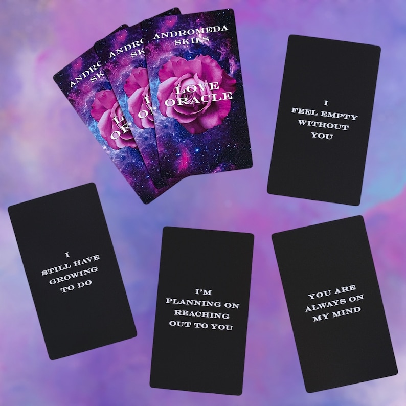 Puede incluir: Un juego de cartas de or&aacute;culo en blanco y negro con un fondo de galaxia y una flor rosa. Las cartas presentan frases como "Estoy planeando contactarte" y "Me siento vac&iacute;o sin ti".
