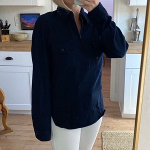 May include: A dark blue long-sleeved shirt with a zipper closure and a single pocket on the left chest.