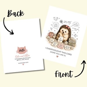 May include: A greeting card with a cartoon hedgehog, a pink bow, and thought bubbles. The front reads "I OVERTHOUGHT THIS CARD (HOPE YOU LIKE IT)". The back has a pink cat logo and the text "Hello" and "HANDMADE WITH".