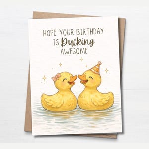 Peut inclure: Carte d'anniversaire avec une illustration à l'aquarelle de deux canards jaunes dans l'eau. L'un porte un chapeau de fête et l'autre un nœud rose. La carte dit : "Hope Your Birthday Is Ducking Awesome."