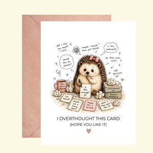 May include: A greeting card with a cartoon hedgehog, a pink bow, and thought bubbles. The card reads "I OVERTHOUGHT THIS CARD (HOPE YOU LIKE IT)". The card is accompanied by a pink envelope.