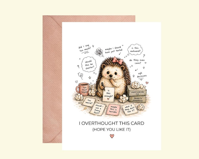 May include: A greeting card with a cartoon hedgehog, a pink bow, and thought bubbles. The card reads "I OVERTHOUGHT THIS CARD (HOPE YOU LIKE IT)". The card is accompanied by a pink envelope.